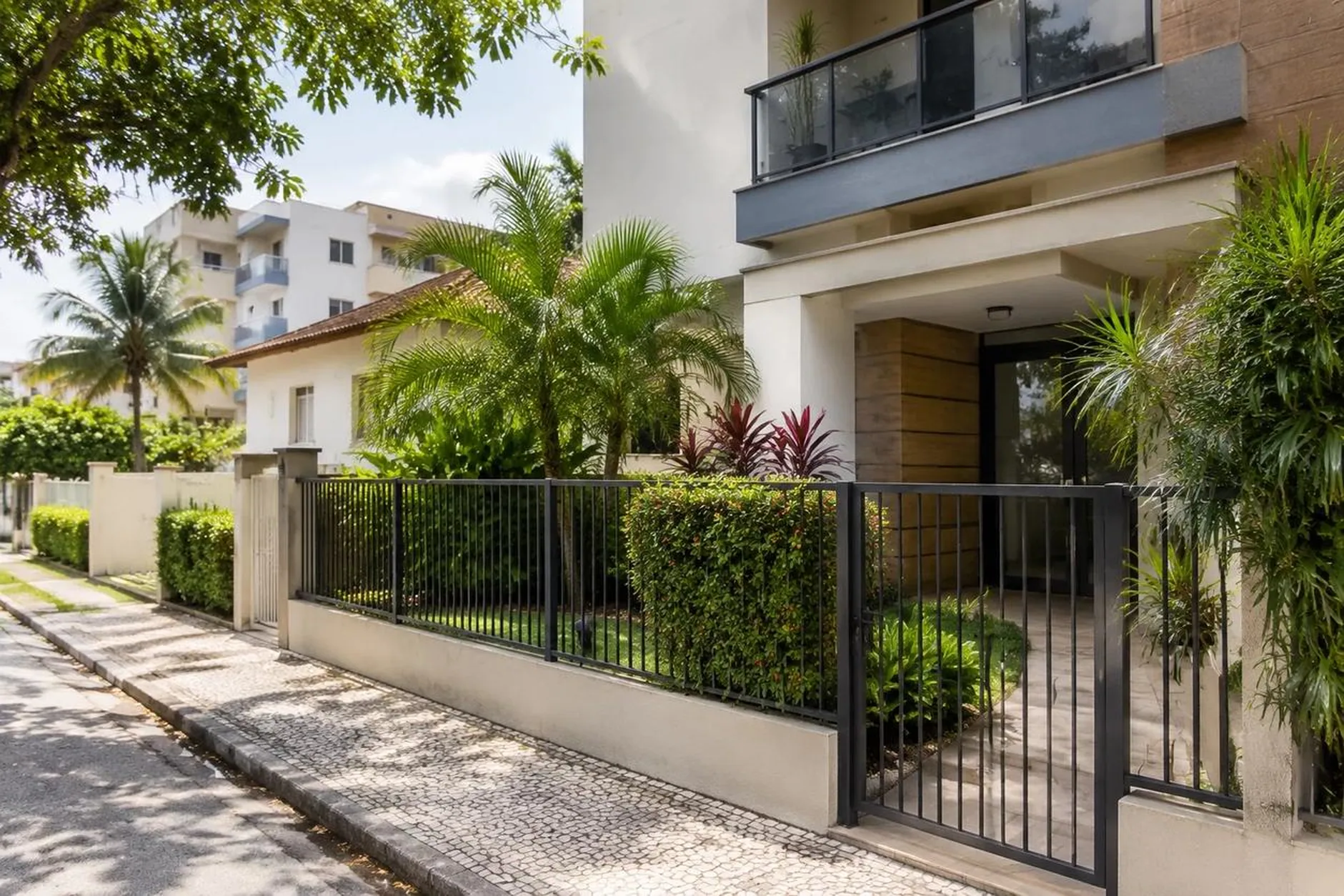 Entrada de um prédio residencial baixo com jardim e portão